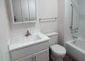 Thumbnail 13 of 14 - A white bathroom with a toilet, sink, and bathtub.