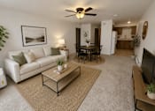 Thumbnail 2 of 20 - A living room with a white couch, a coffee table, and a ceiling fan.