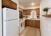 Thumbnail 5 of 20 - A white refrigerator is in a kitchen with wooden cabinets.