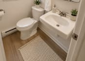 Thumbnail 8 of 20 - A white toilet and sink in a bathroom.