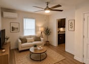 Thumbnail 10 of 20 - A living room with a white couch, a ceiling fan, and a television.