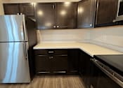 Thumbnail 13 of 34 - a kitchen with black cabinets and a stainless steel refrigerator