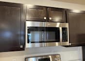 Thumbnail 11 of 34 - a microwave oven in a kitchen with black cabinets
