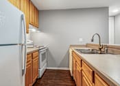 Thumbnail 10 of 19 - A kitchen with a white refrigerator, wooden cabinets, and a stainless steel sink.