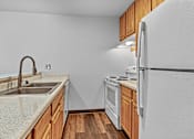 Thumbnail 11 of 19 - A kitchen with a white fridge, sink and wooden cabinets.