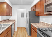 Thumbnail 4 of 19 - A kitchen with brown cabinets and a black refrigerator.