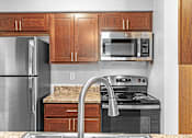 Thumbnail 5 of 19 - A kitchen with a refrigerator, microwave, oven, and sink.