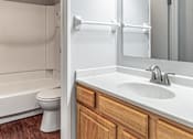 Thumbnail 19 of 20 - A white sink in a bathroom with wood cabinets.