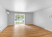 Thumbnail 8 of 19 - A room with wooden floors and a sliding glass door leading to a patio.