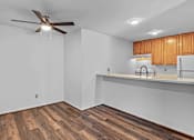 Thumbnail 9 of 19 - A room with a ceiling fan and wooden floors.