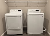 Thumbnail 8 of 21 - Two white front loading washing machines in a laundry room.