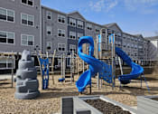 Thumbnail 11 of 15 - We have a large playground with slides and other playground equipment in front of an apartment building