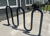 Thumbnail 13 of 15 - A set of black metal bike racks are in front of a building.