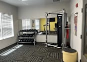 Thumbnail 4 of 15 - A gym room with a weight rack and a bench.