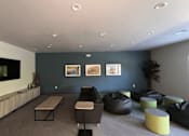 Thumbnail 8 of 15 - A living room with a grey floor and a television on the wall.