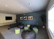 Thumbnail 7 of 15 - A living room with a black couch and green ottomans.