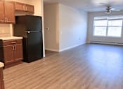 Thumbnail 4 of 21 - A kitchen with a black fridge and wooden cabinets.