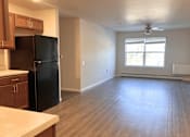 Thumbnail 5 of 21 - A kitchen with a black fridge and wooden cabinets.