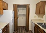 Thumbnail 4 of 11 - A kitchen with a white fridge and wooden cabinets.