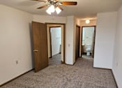 Thumbnail 8 of 11 - A room with a ceiling fan and carpeted floor.