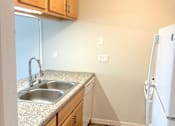 Thumbnail 2 of 4 - A kitchen with a sink and a refrigerator.
