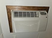 Thumbnail 6 of 19 - an air conditioning unit mounted on a wall with a wooden shelf above it