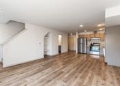 Thumbnail 4 of 38 - A spacious room with wooden flooring and a staircase leading to another level.