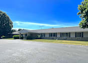 Thumbnail 1 of 6 - A building with a parking lot in front of it.