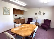 Thumbnail 4 of 6 - A dining room with a wooden table and chairs.