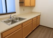 Thumbnail 2 of 4 - A kitchen with a sink and wooden cabinets.
