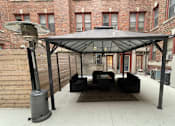 Thumbnail 22 of 25 - A patio with a black umbrella and a black couch.