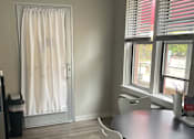 Thumbnail 20 of 25 - A room with a table, chairs, and a window with red blinds.