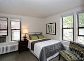 Thumbnail 5 of 25 - A bedroom with a bed, nightstand, and window.