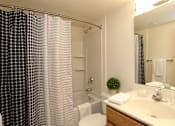 Thumbnail 11 of 25 - A bathroom with a shower curtain, toilet, sink, and mirror.
