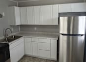 Thumbnail 2 of 8 - A kitchen with white cabinets and a stainless steel refrigerator.