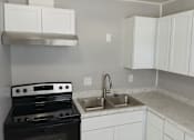 Thumbnail 3 of 8 - A kitchen with a black stove top oven and white cabinets.