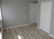 Thumbnail 6 of 8 - A room with two white doors and wooden flooring.