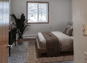 Thumbnail 3 of 3 - A bedroom with a bed, a potted plant, and a window.