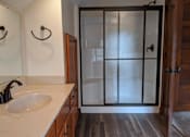 Thumbnail 10 of 29 - A bathroom with a sink, mirror, and shower door.