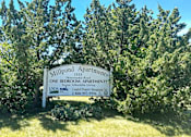 Thumbnail 2 of 14 - A sign for Millpond Apartments stands in front of a tree.