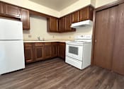 Thumbnail 5 of 14 - A white refrigerator stands in a kitchen with wooden cabinets and a white stove.
