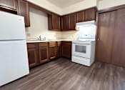 Thumbnail 4 of 14 - A kitchen with white appliances and brown cabinets.