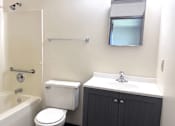 Thumbnail 8 of 14 - A white toilet sits next to a bathtub in a bathroom.