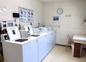 Thumbnail 9 of 14 - A laundromat with washers and dryers and a clock on the wall.