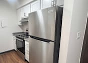Thumbnail 5 of 14 - A stainless steel refrigerator in a kitchen with white cabinets.
