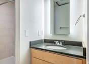 Thumbnail 12 of 31 - A bathroom with a sink, mirror, and shower.