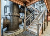 Thumbnail 22 of 31 - A large metal pipe structure in a building with a staircase.