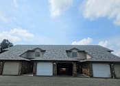 Thumbnail 1 of 16 - A house with a garage and a brick wall.