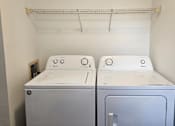 Thumbnail 14 of 16 - Two front loading washing machines in a small laundry room.