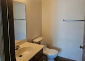 Thumbnail 12 of 16 - A bathroom with a toilet, sink, and mirror.